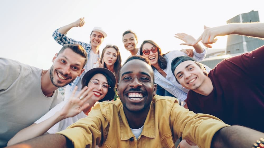 A diverse group of friends smiling together in a group photo outdoors.